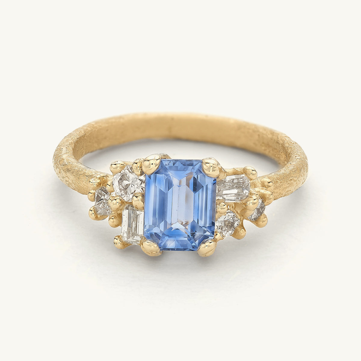 Blue sapphire engagement ring with clusters of mixed cut diamonds. Handcrafted in London with 100% recycled gold and responsibly sourced gemstones.