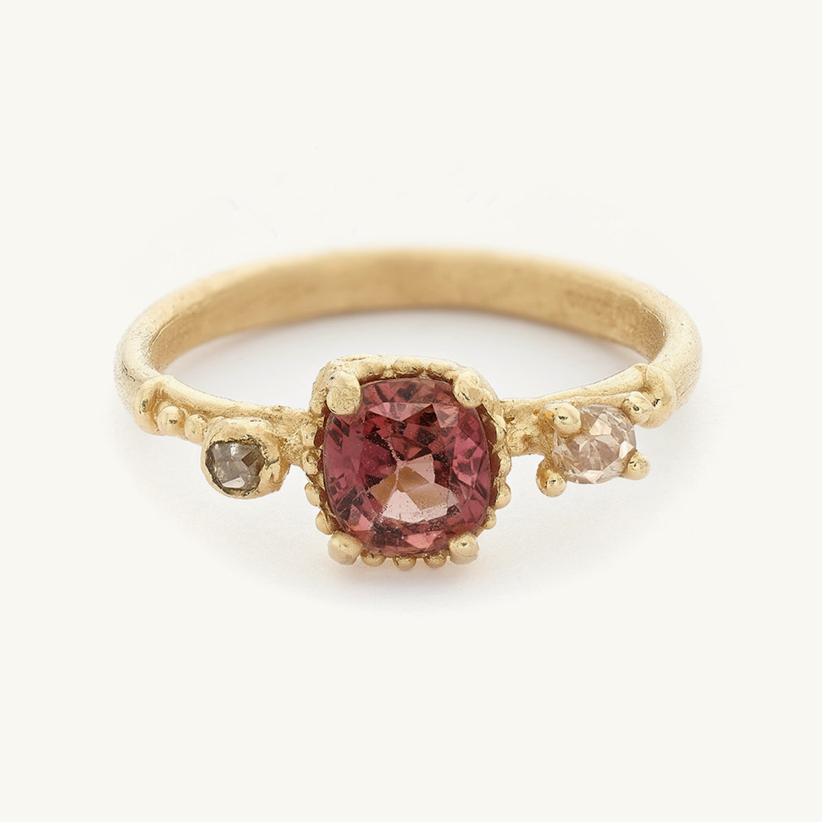 Ruth Tomlinson alternative engagement ring handcrafted in 14ct yellow gold with a cushion cut pink sapphire framed by golden details and two antique diamonds