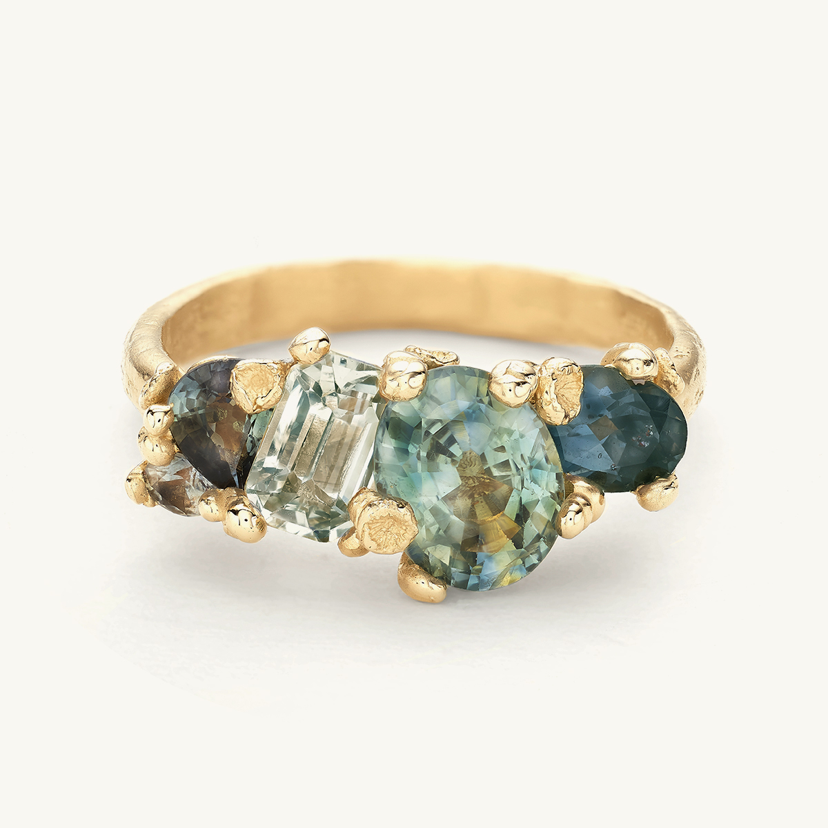 Statement one-of-a-kind ring with a cluster of mixed cut sapphires in tones of green and blue. 