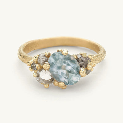 A beautiful one-of-a-kind engagement ring with an oval sapphire and grey diamond clusters. 