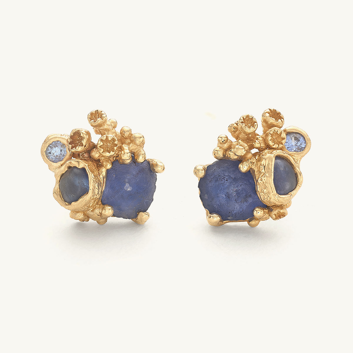 Pair of gold and sapphire stud earrings with a trio of mixed cut sapphires and barnacle details. 
