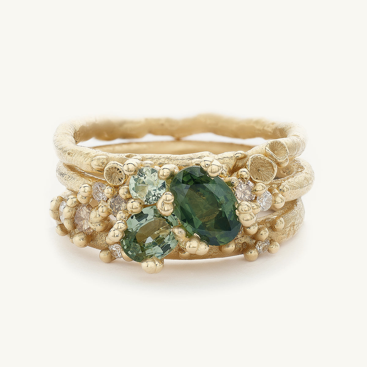 Ruth Tomlinson Ocean inspired engagement ring stack with green sapphires and champagne diamonds and organic details made from recycled gold