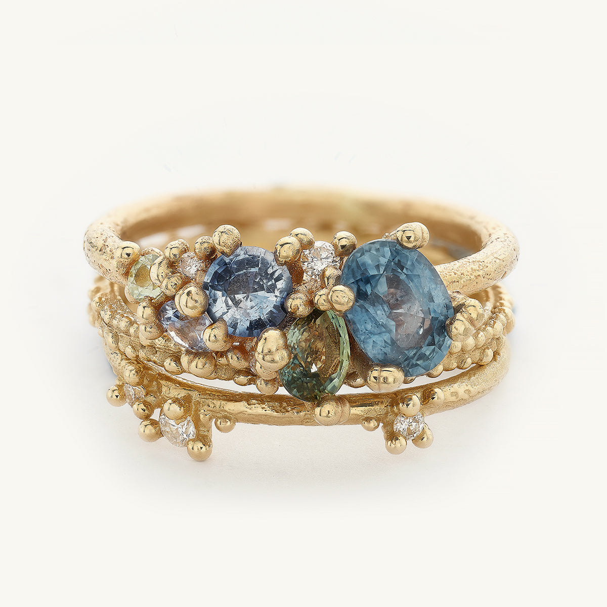 Ruth Tomlinson Ocean Inspired engagement ring stack with blue and green sapphires and diamonds made from recycled gold