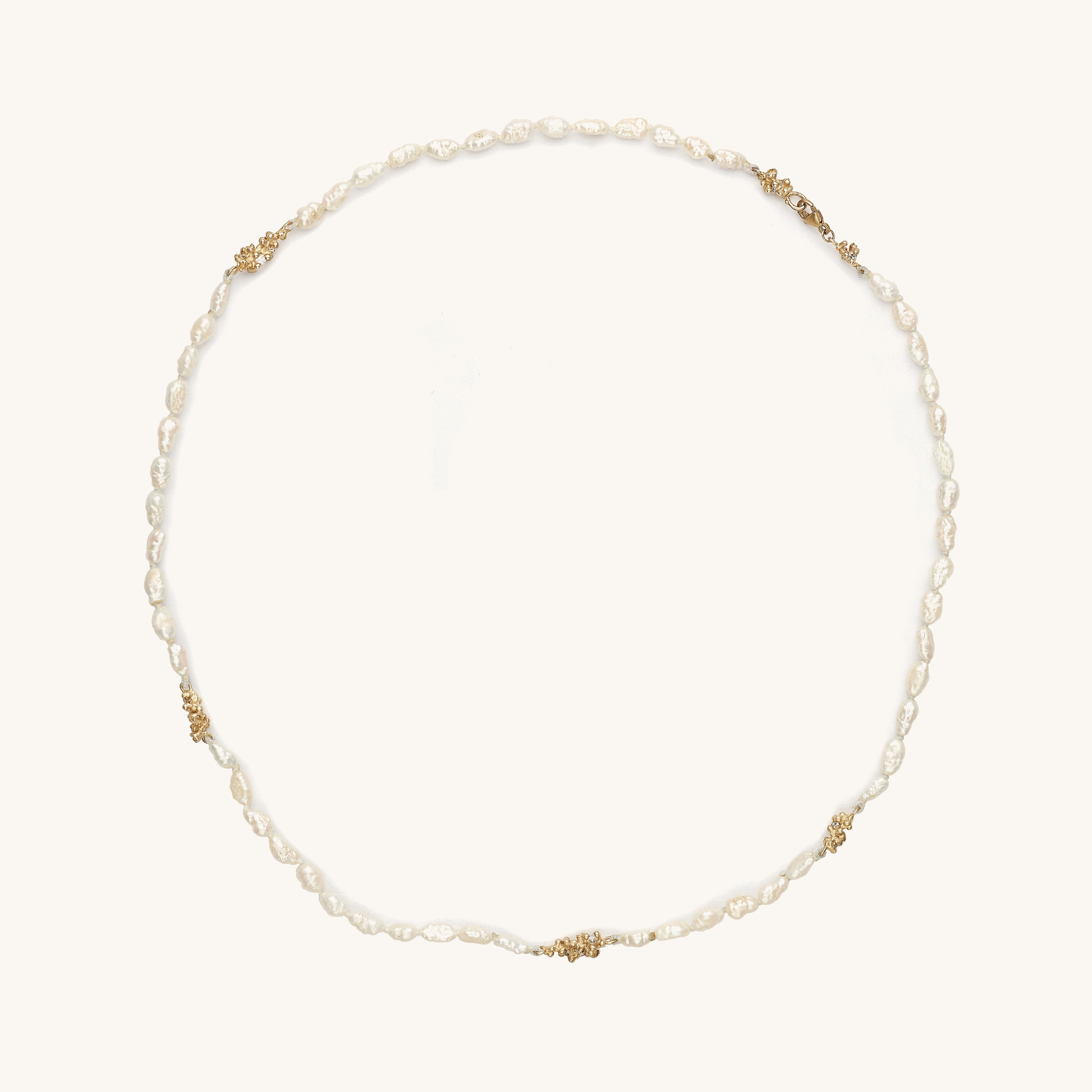 Handcrafted freshwater pearl necklace punctuated with ocean inspired clusters of golden granules and diamonds. 