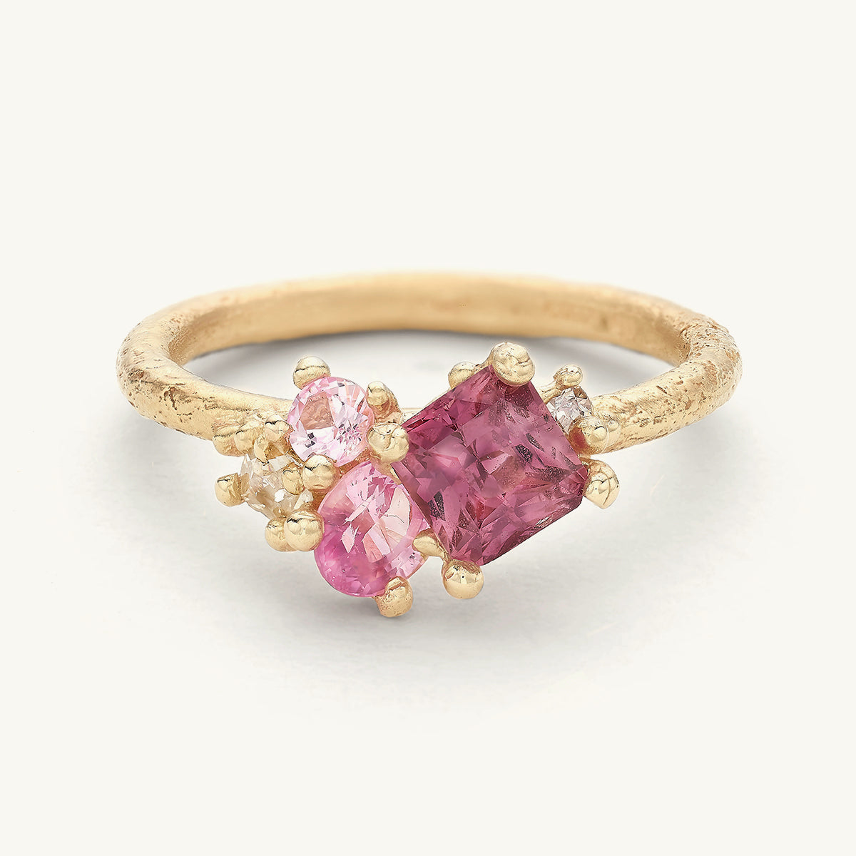 A unique engagement ring with an asymmetric cluster of pink sapphires and diamonds. 