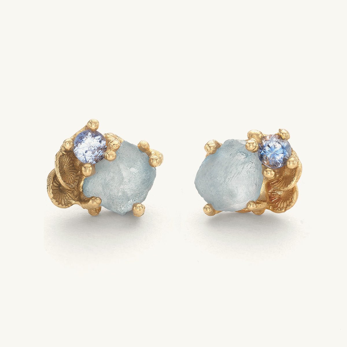 Pair of handcrafted earrings with gold barnacle accents and mixed cut blue sapphires on a white background