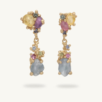 Pair of gold earrings with mixed cut sapphires in pastel tones on a white background. Handcrafted in London with recycled gold and responsibly sourced gemstones. 